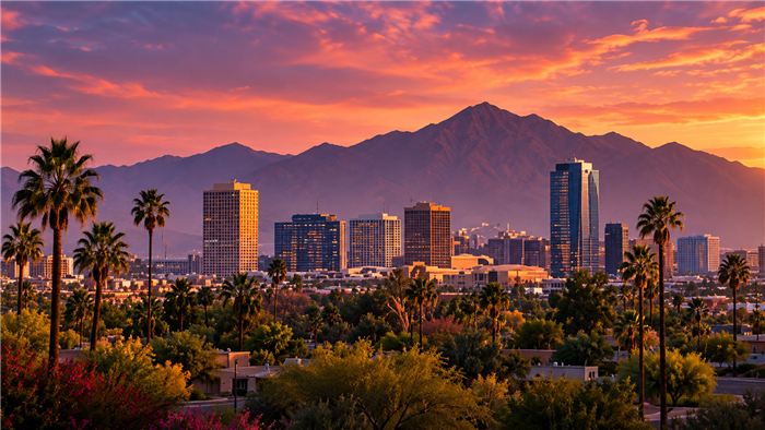 Downtown Phoenix skyline at dusk with palm trees and mountains behind